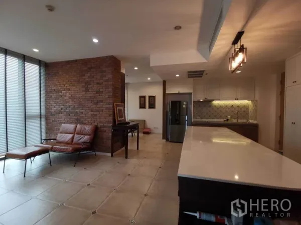 คอนโด ให้เช่าหรือขายในBang Rak, Bangkok - ห้องนั่งเล่นและครัวพร้อมไอส์แลนด์ยาว ผนังอิฐ และมุมนั่งพักผ่อน