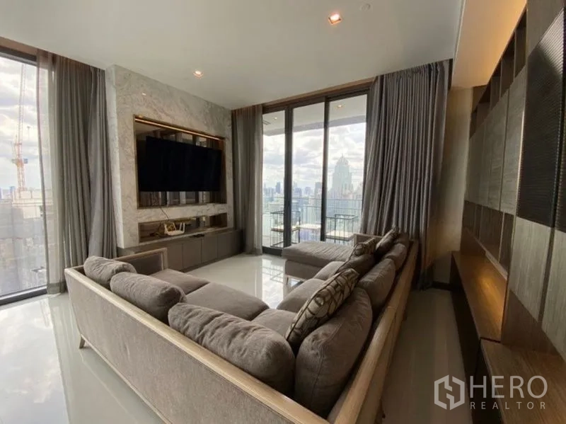 Condominium for rent in Khlong Toei, Bangkok - Living area facing floor-to-ceiling balcony doors overlooking the Bangkok skyline.