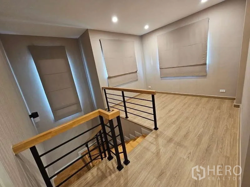Detached House for rent in Bang Phli, Samut Prakan - Upstairs landing with wood flooring and a metal-and-wood staircase railing.