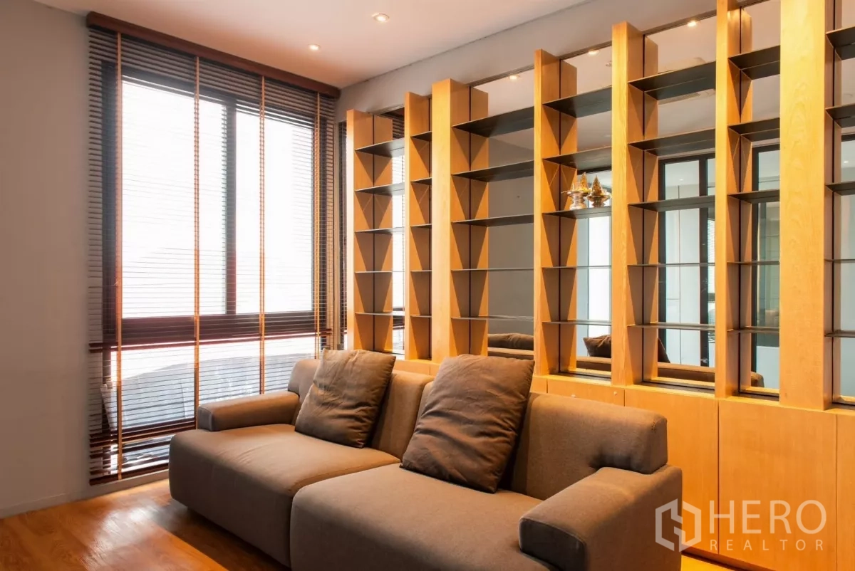 Townhouse for rent in Lat Phrao, Bangkok - Cozy living room with large sofa and decorative shelving wall.