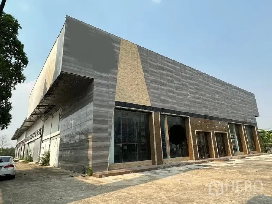Warehouse for rent in Lam Luk Ka, Pathum Thani - Modern showroom and warehouse exterior with full-height glass facade and driveway in Lam Luk Ka.