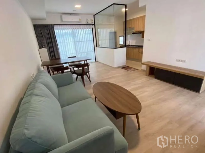 Townhouse for rent in Bang Phli, Samut Prakan - Living area facing the enclosed kitchen with glass partition and dining set.