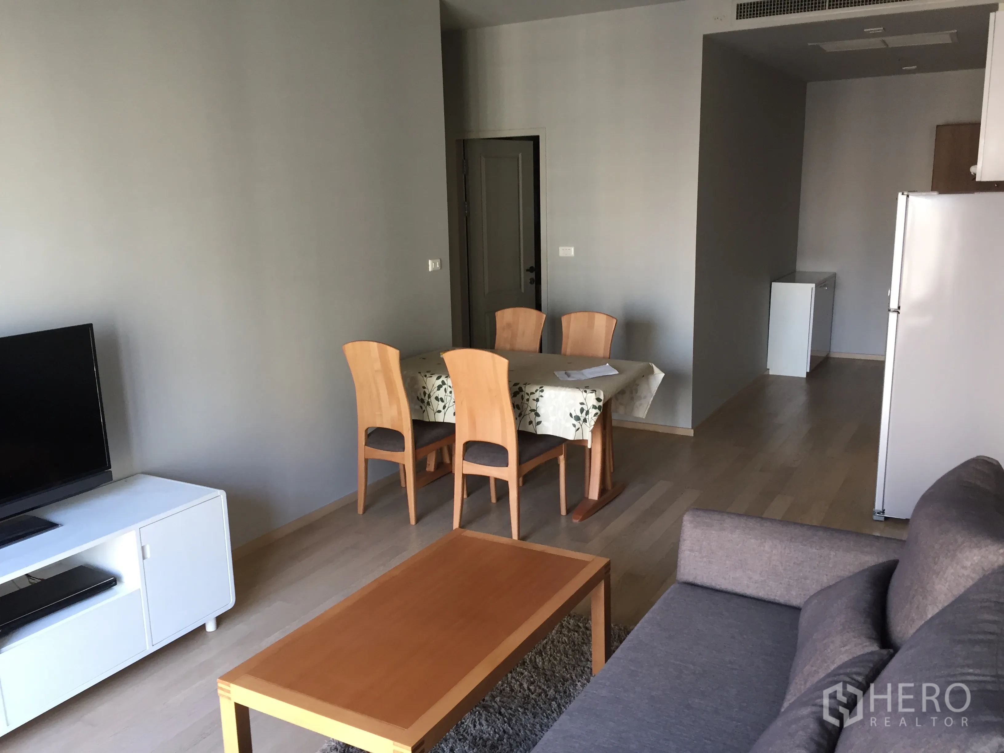 Condominium for rent in Bangkok - Bright living room view with TV console and a four-seat dining table in a modern condo.
