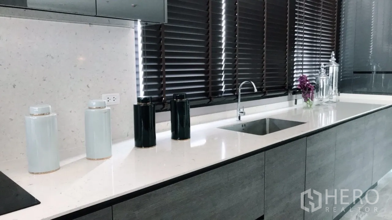 Condominium for rent or sale in Huai Khwang, Bangkok - Sleek kitchen with white quartz countertop, under-mount sink, and dark window blinds.