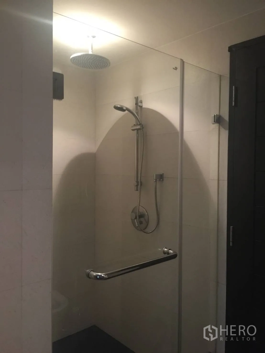 Condominium for rent in Watthana, Bangkok - Glass-enclosed shower with rain showerhead and handheld sprayer in a tiled bathroom.