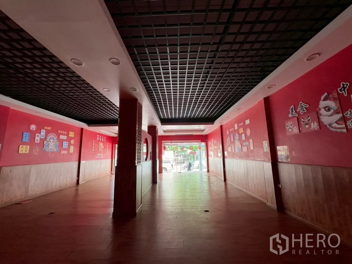 店屋 出租在Watthana, Bangkok - 纵深零售大厅通向玻璃入口，黑色格栅吊顶与墙面图案
