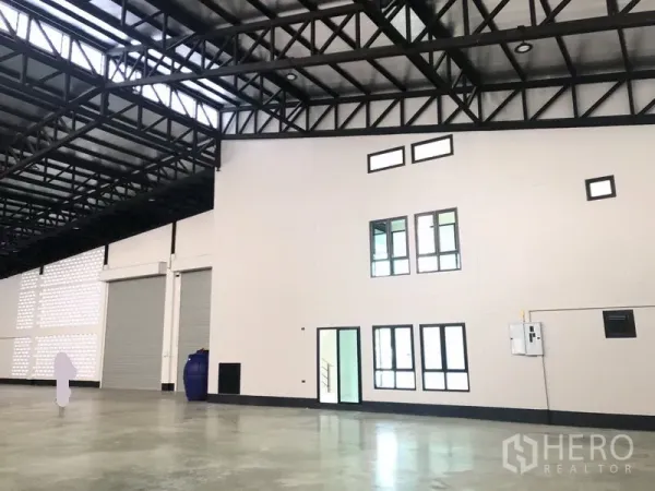 工厂 出售在Pathum Thani - 仓库视角，可见多窗办公区与两扇大型卷帘门。