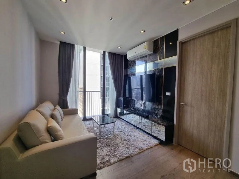 Condominium for sale - Living room with TV wall, shag rug and sliding door to balcony at Sukhumvit condo.