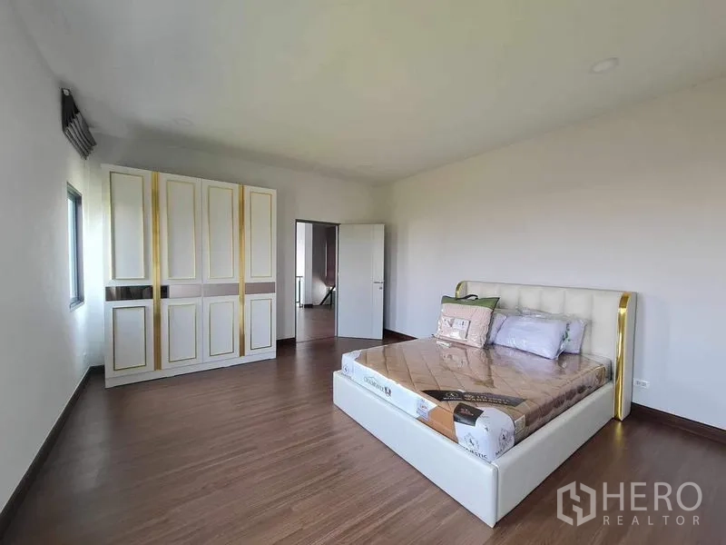 Detached House for rent or sale in Bang Phli, Samut Prakan - Spacious bedroom with white and gold wardrobe and upholstered bed.
