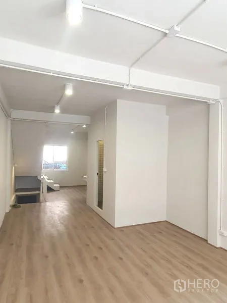 Shophouse for rent in Phra Khanong, Bangkok - Spacious upper floor with wood floors, a partitioned room and a window bringing in natural light.