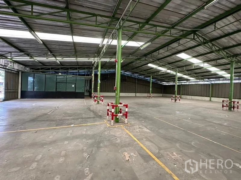 Warehouse for rent in Prawet, Bangkok - Warehouse floor with green columns and a glass supervisor room.