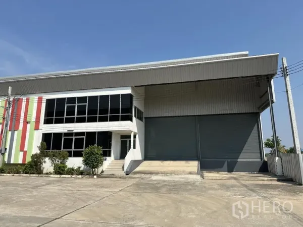 货栈 出租在Samut Prakan - 仓库外观，带大型卷帘门、装卸平台和玻璃办公楼
