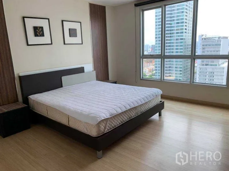 Condominium for rent in Bang Rak, Bangkok - Master bedroom with large windows, city view, queen bed and light wood flooring.