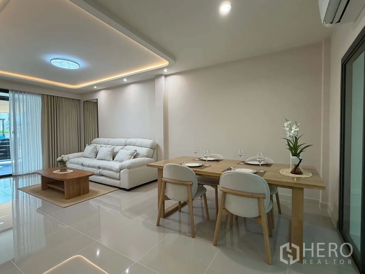 ทาวน์เฮาส์ for rent in Bang Phli, Samut Prakan - โซนรับแขกและรับประทานอาหารแบบโอเพ่น มีโซฟา โต๊ะอาหารหกที่นั่ง และประตูกระจกบานเลื่อน