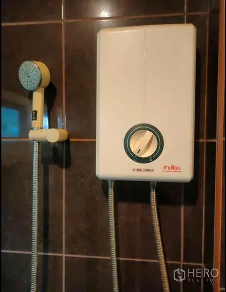 Detached House for rent in Wang Thonglang, Bangkok - Shower area with wall-mounted water heater and handheld shower on dark tiles.