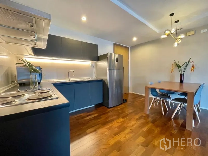 Condominium for rent or sale in Khlong Toei, Bangkok - Modern kitchen with cooktop, range hood, and stainless refrigerator.