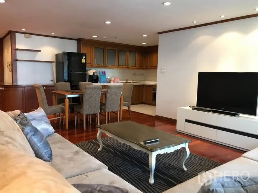 公寓 出租在Watthana, Bangkok - 开放式客厅，米色沙发、电视柜、餐桌与木质橱柜的厨房，铺木地板