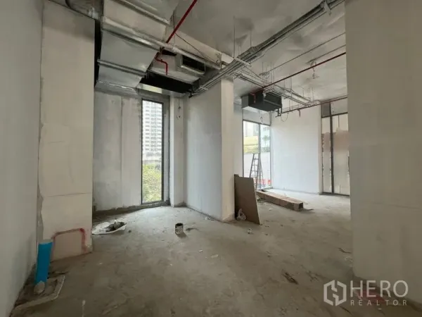 零售空间 出租在Khlong Toei, Bangkok - 未完成装修的店铺内景，通风风管、狭长落地窗与水泥地面，靠近 Phrom Phong 轻轨，适合自定义装修。