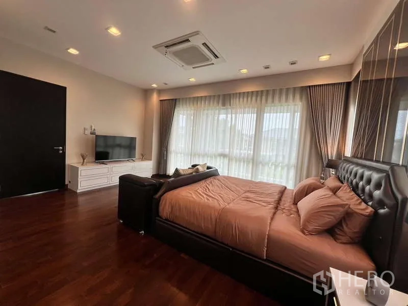 独立式住宅 出租或出售在Lat Krabang, Bangkok - 宽敞主套房，电视柜、大窗与透光窗帘。