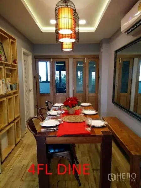 Shophouse for sale in Phra Khanong, Bangkok - Warm dining room with a wooden table set, pendant lights, large wall mirror and sliding doors.