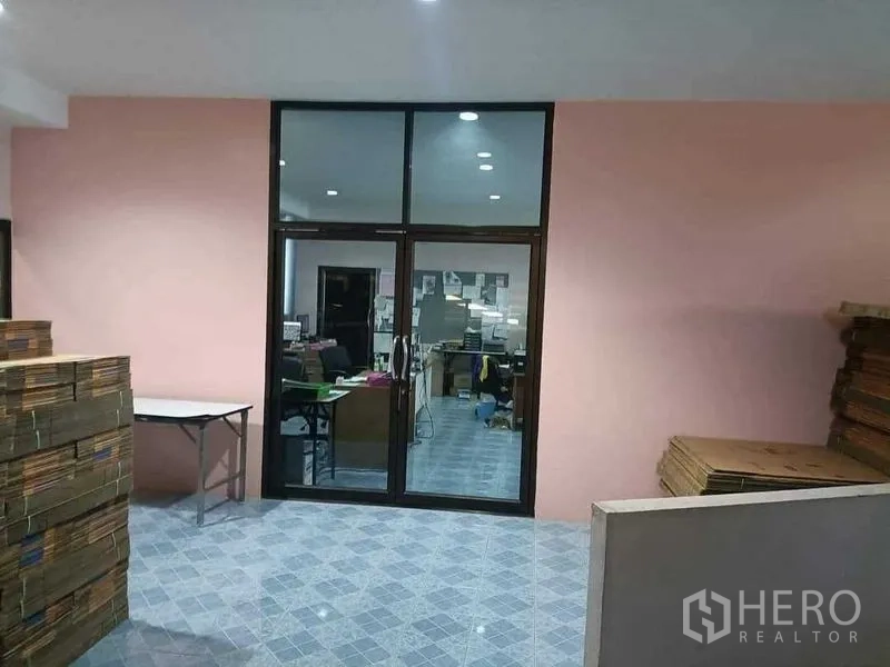 Warehouse for sale in Samut Sakhon - Glass-partitioned office room inside the warehouse with tiled floors and recessed ceiling lights.