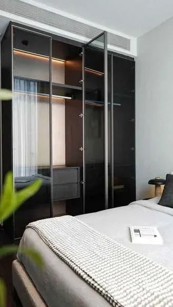 公寓 出租或出售在Watthana, Bangkok - 卧室配玻璃衣柜与氛围灯，床铺整洁。