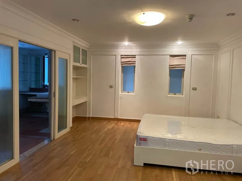 Condominium for rent in Watthana, Bangkok - Large bedroom with sliding doors to an ensuite bathroom and polished hardwood floors.