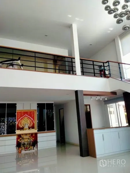 独立式住宅 出售在Thawi Watthana, Bangkok - 挑高客厅带夹层、吊灯与内置柜体。