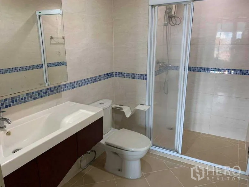 Condominium for rent in Bang Rak, Bangkok - Bathroom view of vanity, mirror and sliding glass shower enclosure.