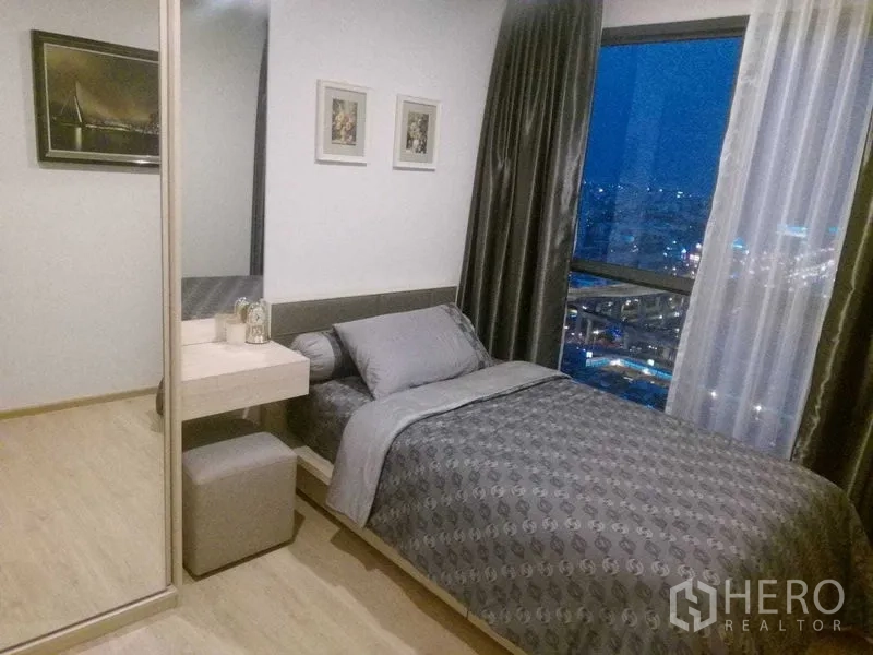 公寓 出租在Bang Na, Bangkok - 温馨次卧，单人床、镜面衣柜与大窗，可见城市夜景。