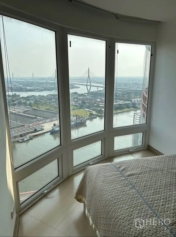公寓 出租或出售在Yan Nawa, Bangkok - 转角卧室的弧形落地窗，框出河景与普密蓬大桥。