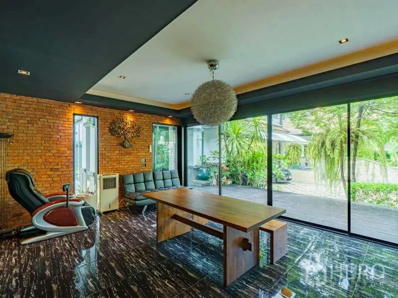 独立式住宅 出售在Suan Luang, Bangkok - 多功能房，裸砖墙、大型木桌与推拉玻璃门通向露台。