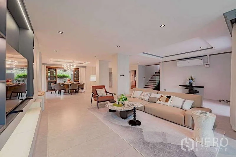 Detached House for rent or sale in Phra Khanong, Bangkok - Open-plan living and dining area with neutral decor and a central staircase.