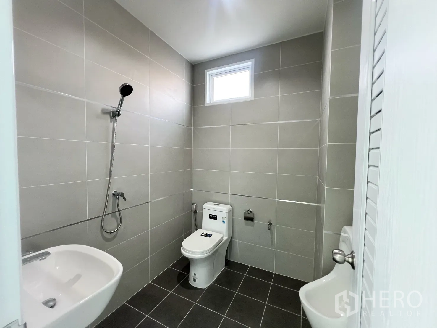 Warehouse for rent in Mueang Samut Prakan, Samut Prakan - Modern restroom with shower, toilet, sink and grey wall tiles.