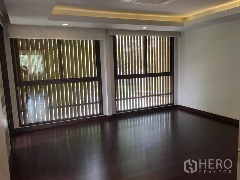 独立式住宅 出租在Sathon, Bangkok - 卧室深色木地板，宽窗配竖向百叶