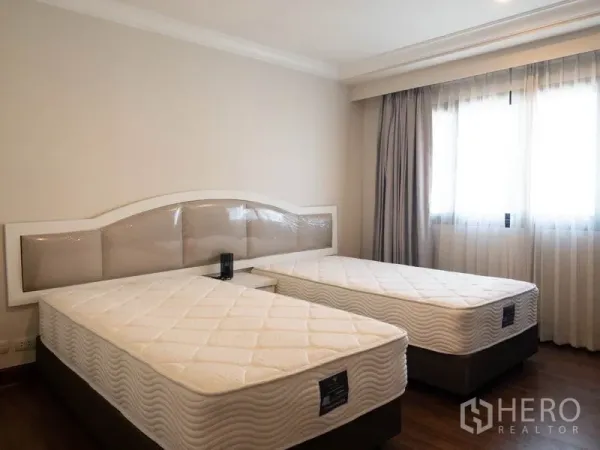 公寓 出租在Watthana, Bangkok - 双床卧室，临窗采光良好，浅色窗帘与简约配色。