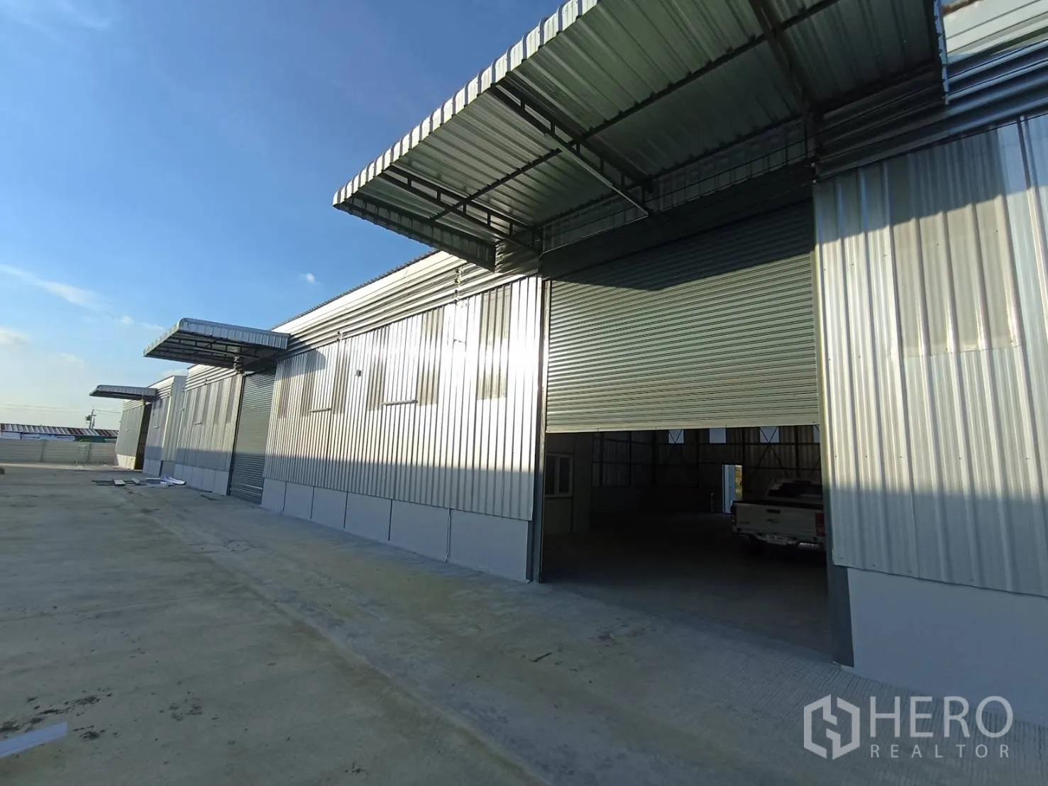 Warehouse for rent in Mueang Samut Prakan, Samut Prakan - Exterior view of multiple roller shutter bays with covered loading canopies.