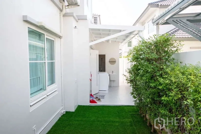 Detached House for rent in Bang Phli, Samut Prakan - Side yard with green lawn leading to covered laundry and service zone.