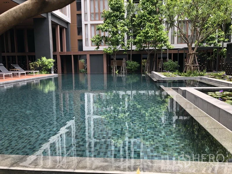 Condominium for rent in Watthana, Bangkok - Close view of tiled swimming pool with landscaped greenery and water features.