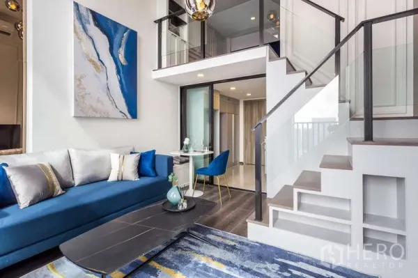 Condominium for rent - Another angle of the loft living room showing stairs, mezzanine, and blue sofa.