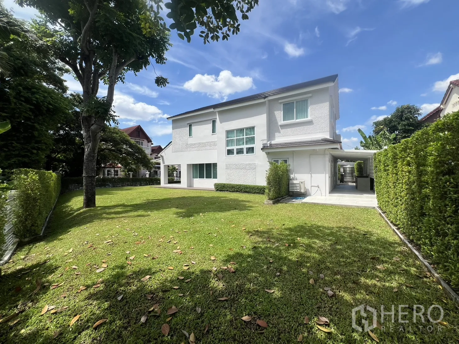 Detached House for rent in Mueang Samut Prakan, Samut Prakan - Expansive backyard lawn with mature trees behind the white house.