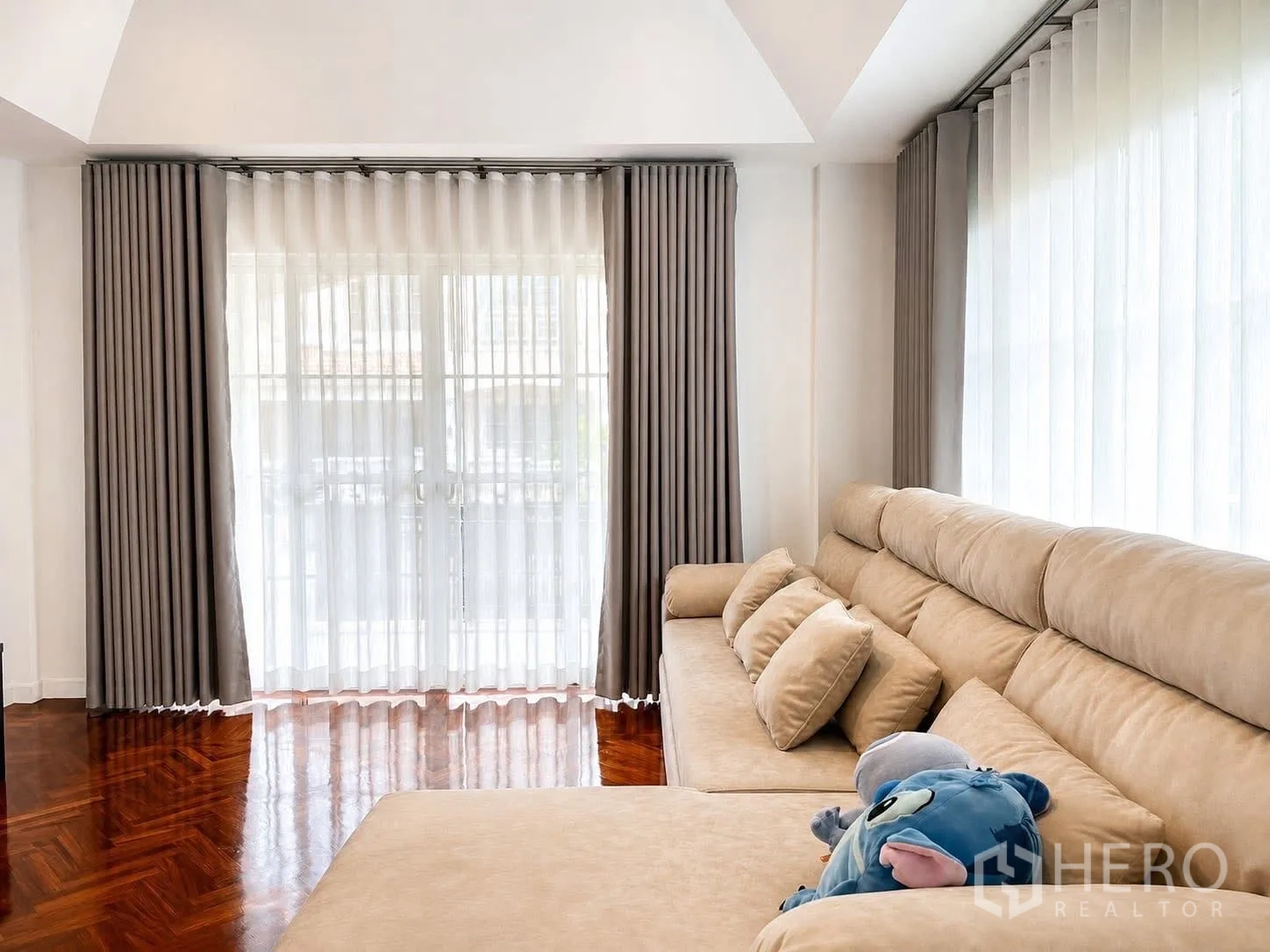 独栋房屋 for rent in Prawet, Bangkok - 客厅配大型米色组合沙发与两组玻璃门和窗帘。