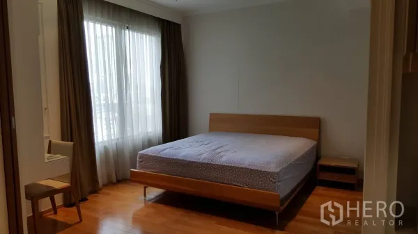 公寓 出租在Khlong Toei, Bangkok - 采光明亮的卧室，配大床、木地板、书桌及带窗帘的大窗。