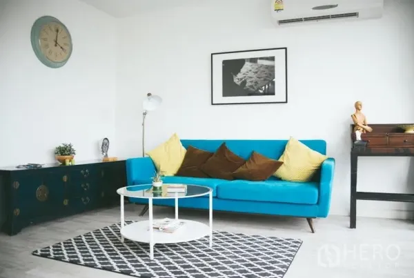 Condominium for sale in Phra Khanong, Bangkok - Modern living room with blue sofa, round coffee table and patterned rug.