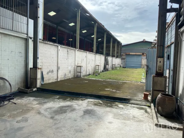 Retail Space for rent in Yan Nawa, Bangkok - Open yard with concrete driveway leading to a blue roller door and partial roof cover.