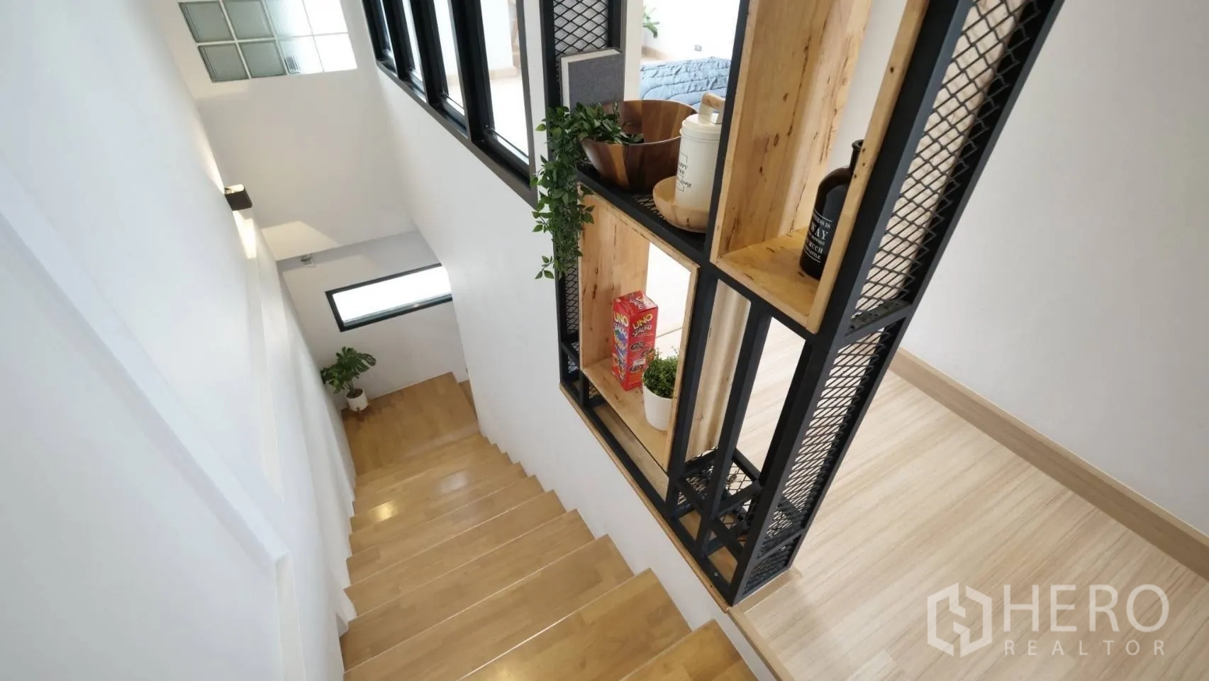 Townhouse for rent in Huai Khwang, Bangkok - Wood staircase with custom metal-and-wood shelving divider and decorative plants.