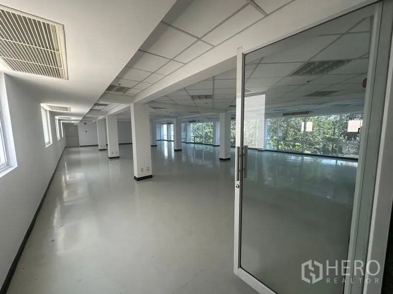 办公空间 出租在Phaya Thai, Bangkok - 开放式办公楼层，玻璃门入口、网格吊顶、空调出风口与侧窗，引入充足自然光。