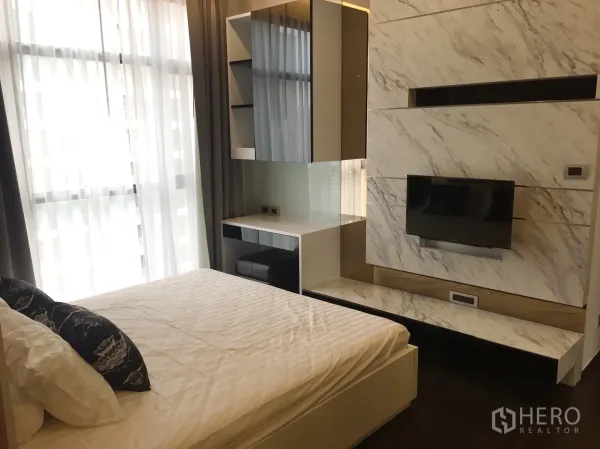 Condominium for rent in Watthana, Bangkok - Bright bedroom with floor-to-ceiling windows, sheer curtains, bed and marble TV wall.