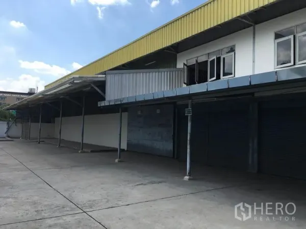 Warehouse for rent in Prawet, Bangkok - Exterior of a Prawet, Bangkok warehouse with covered loading bays, roller shutters and a wide concrete yard.