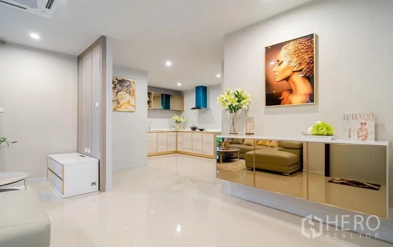 Detached House for sale in Lam Luk Ka, Pathum Thani - Open-plan living and kitchen with built-in console and artwork.